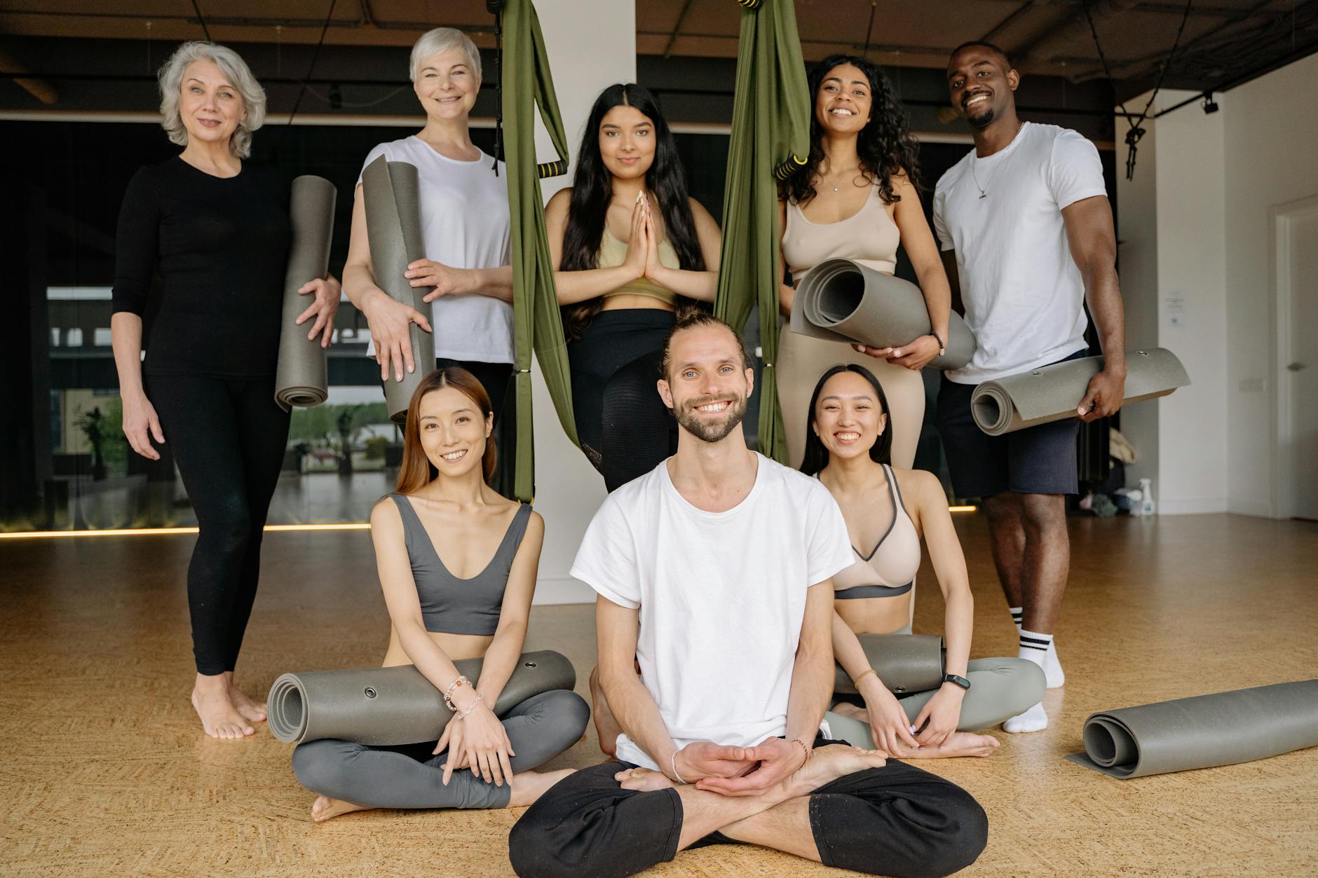 Diverse group of people smiling and preparing for a yoga class.